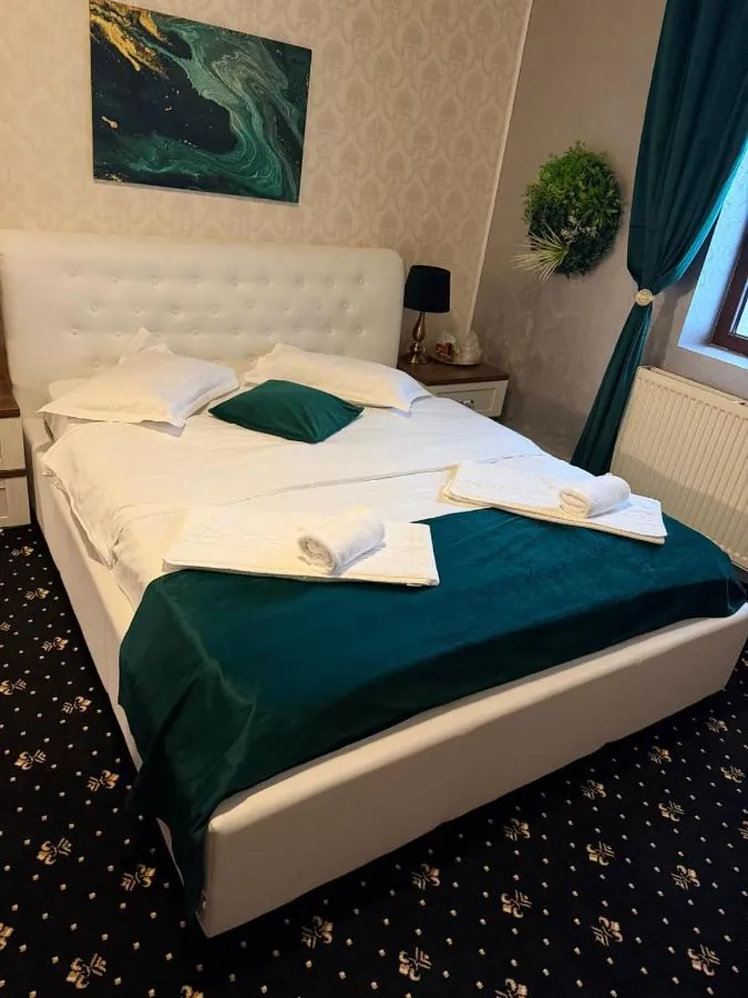 Cameră dublă superioară cu pat tapițat alb și cuvertură verde